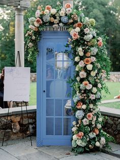 a blue phone booth decorated with flowers and greenery