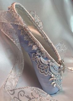 a pair of blue ballet shoes on a white satin fabric with silver sequins