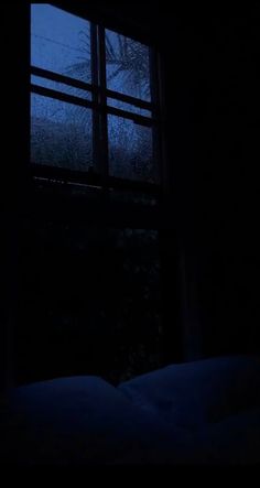 a dark room with a bed and window at night