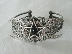 This beautiful silver plated filigree cuff bracelet has a silver plated triple moon design and a pewter silver pentacle with an obsidian setting. Adjustable. Mystical Silver Jewelry For Festival, Gothic Silver Jewelry For Festival, Gothic Silver Festival Jewelry, Mystical Silver Jewelry With Intricate Design, Mystical Adjustable Jewelry For Halloween, Adjustable Mystical Jewelry For Halloween, Silver Gothic Bracelets For Halloween, Mystical Adjustable Halloween Jewelry, Gothic Silver Bracelets For Halloween