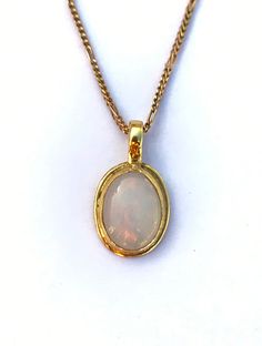 Light up your attire with this pendant necklace, Featuring a simple yet elegant design, this yellow gold opal solitaire necklace is sure to fascinate. The bezel set cabochon opal allures with its delightful play of colors. Gemstone - Opal Shape - Oval  Size - Free Size Material - 925 Sterling Silver Chain - 925 Sterling Silver Oval Ethiopian Opal Necklace For Formal Occasions, Formal Oval Ethiopian Opal Necklace, Formal Ethiopian Opal Oval Necklace, Gold Opal Necklace With Oval Cabochon, Elegant Ethiopian Opal Oval Pendant Necklace, Elegant Ethiopian Opal Necklace In Gold, Bezel Set Cabochon, Oval Necklace, Opal Pendant Necklace