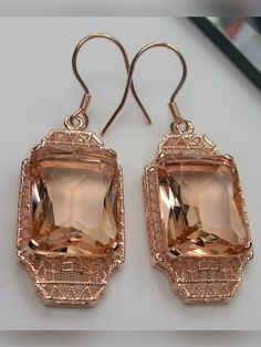 Simulated Peach Topaz Rose Gold plated Sterling Silver EarringsLantern Design#E13 Inspired by the Art Deco period, these lovely antique reproduction earrings are rose gold overlay on sterling silver. Created from an antique brooch, each earring has a 9 carat simulated peach topaz surrounded by filigree. The man-made gemstones are 15mm x 12mm each. The earrings are 1 3/4" long and 9/16" at their widest point. These lovely dangle earrings are marked 925 for sterling silver. These earrings are a wo Rectangular Rose Gold Jewelry For Evening, Rectangular Rose Gold Jewelry For Party, Elegant Copper Jewelry For Parties, Rose Gold Vintage Jewelry For Evening, Vintage Rose Gold Jewelry For Evening, Elegant Copper Jewelry With Matching Earrings, Antique Rose Gold Earrings For Formal Occasions, Elegant Rectangular Jewelry With Intricate Design, Elegant Copper Earrings For Wedding