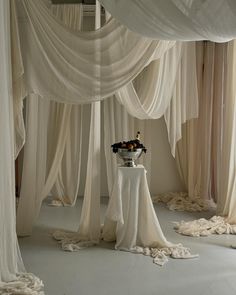 a room with white drapes and flowers on the table