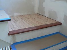 a wooden step with blue tape on it in the corner of a room under construction