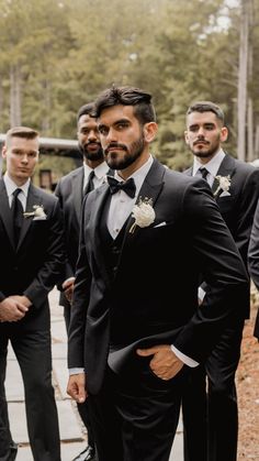 a group of men standing next to each other wearing suits and bow ties on their heads