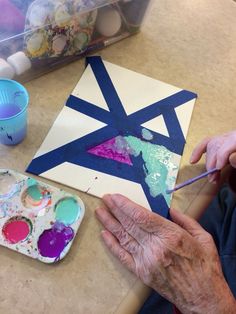 an older person is painting on a piece of paper