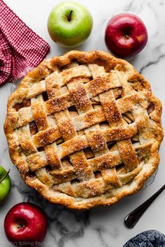 an apple pie on a marble table with apples around it