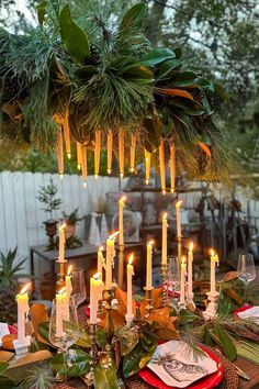 an outdoor table with candles and greenery