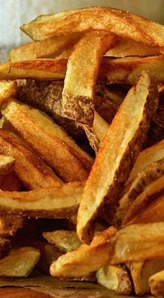 a pile of french fries sitting on top of a wooden cutting board