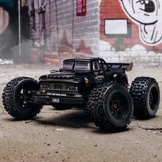 a toy truck is parked in front of a graffiti covered wall