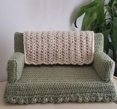 a crocheted couch sitting on top of a table next to a potted plant