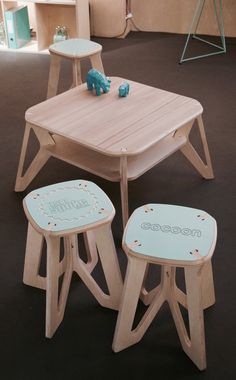 three wooden stools and a table with an elephant on it in a room filled with children's furniture