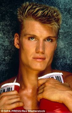 a young man with blonde hair holding two cups