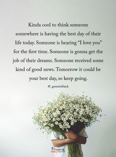 a woman holding a bouquet of daisies in front of a white wall with a quote on it