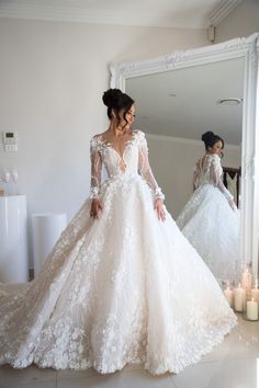 a woman in a wedding dress looking at herself in the mirror with candles around her