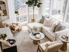 a living room filled with white furniture and tall buildings in the backgroung