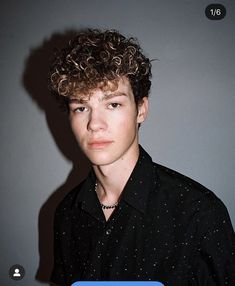 a young man with curly hair wearing a black shirt