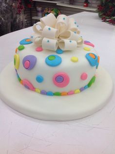 a white cake with multicolored polka dots on it sitting on top of a table