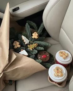 two cups of coffee sitting on top of a car seat next to cookies and candy