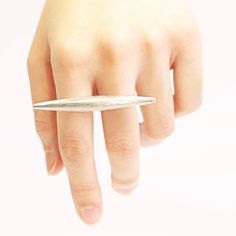 a woman's hand with a ring on top of her finger and an object in the middle