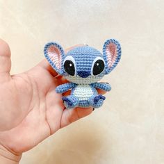 a small crocheted blue and white stuffed animal in someone's left hand