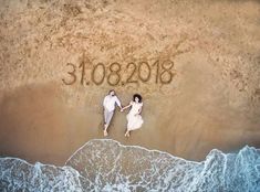 an aerial view of two people holding hands and writing on the sand at the beach