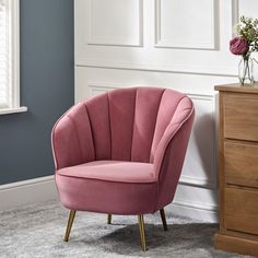 a pink chair sitting on top of a carpeted floor next to a wooden dresser