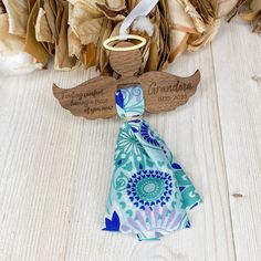 an angel ornament on top of a table next to dried flowers and leaves