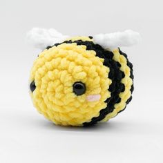 a yellow and black crocheted bee with white wings on it's head