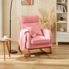 a pink rocking chair with a blanket on it in front of a white bookcase