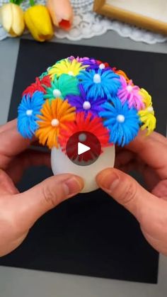 a person holding a small colorful object in their hands with the video below it showing how to make an origami flower arrangement