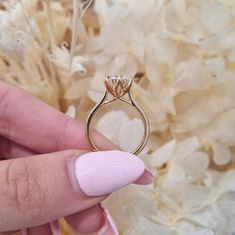 a woman's hand holding a gold ring with a diamond on it