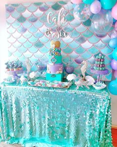 a table topped with lots of cake next to a wall covered in blue and pink balloons