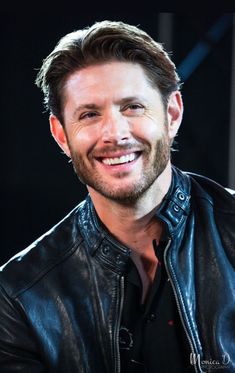 a smiling man wearing a black leather jacket