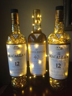 two bottles of macallan are lit up with fairy lights on the top and bottom