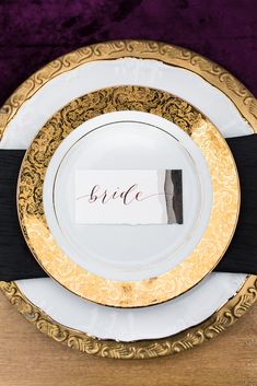 a plate with a place card on it sitting on top of a purple table cloth