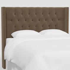 an upholstered headboard on a bed with white sheets