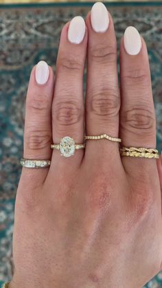 a woman's hand with three different rings on her left and the middle finger