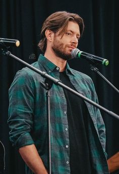 a man standing in front of a microphone with his hands on his hips and looking to the side