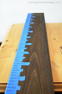 a blue ruler sitting on top of a wooden table next to a piece of wood