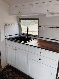 a kitchen area with white cabinets and black counter tops in a mobile home or camper