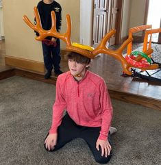 two boys are sitting on the floor with fake antlers