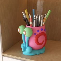 a cup with pens and pencils in it on a shelf next to a ruler