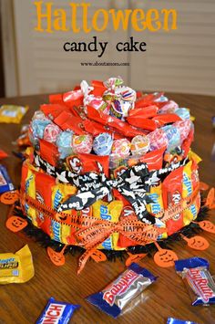 a halloween candy cake on a table with candies scattered around it and the words, happy halloween candy cake