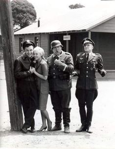 an old black and white photo of four people in uniforms standing next to a telephone pole