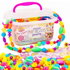 a plastic tub filled with lots of colorful beads next to a pink handle bag full of candy