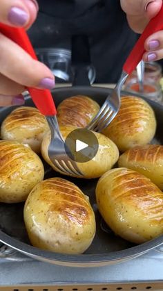 a person holding a fork in a pan filled with potatoes