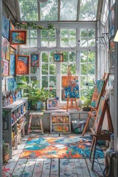 an artist's studio with lots of paintings on the walls and floor, including easels