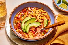 a bowl of mexican soup with avocado and tortilla chips