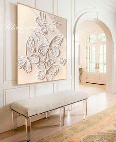 a white bench sitting in front of a wall mounted butterfly art on it's side